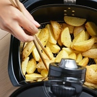 Person picking potato chips out of an air fryer