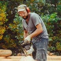 person using a chainsaw with headphones on