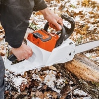 Man hands holding an electric chainsaw.