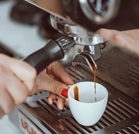 Professional espresso machine pouring fresh coffee into white ceramic cup